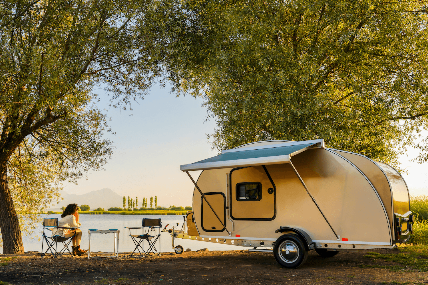 RV campsite setup beside pristine lake with awning extended for outdoor living